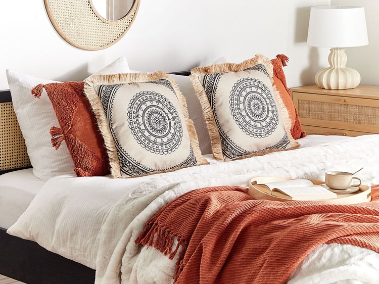 Dekoratives Schlafzimmer mit Kissen, Decke und Nachttischlampe für eine gemütliche Atmosphäre.