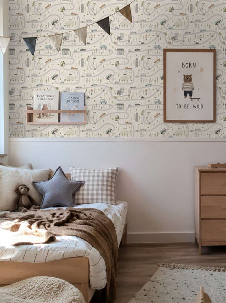 Kinderzimmer mit Tapete mit Straßenmuster, Holzmöbeln, Bett mit Kissen und Deko, helle Atmosphäre.