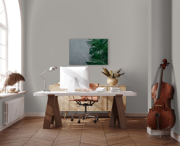 Ein modern eingerichtetes Arbeitszimmer mit einem Schreibtisch, Computer, Schreibtischstuhl, Sideboard und Wandbild mit Palmenmotiv.