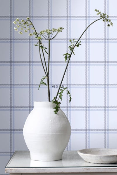 Dekorative Szene mit einer weißen Vase, Pflanzen und einer Tapete mit Karomuster