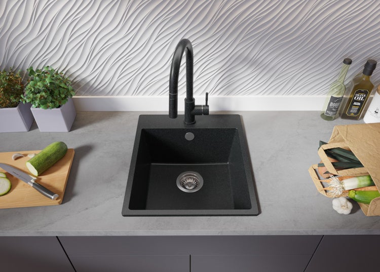 Schwarzes Küchenspülbecken mit Armatur in moderner Küchenszene mit Gemüse
