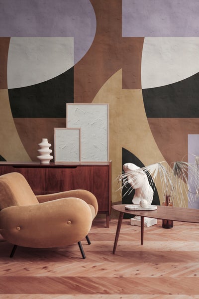 Modernes Zimmer mit abstrakter Wandtapete, Holzkommode und Samtsessel vor großflächigen geometrischen Formen.
