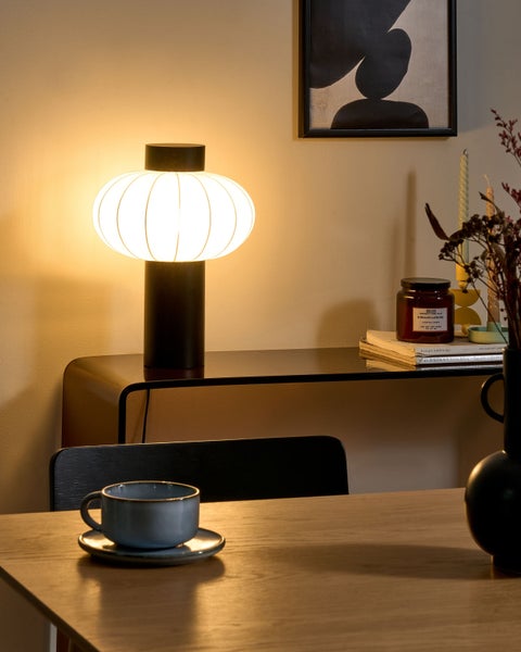 Dekorative Szene mit Tischlampe, Tasse, Kerze und abstrakter Kunst