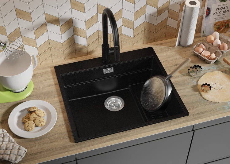 Küchenszene mit schwarzer Spüle, Armatur, Backzutaten und Kochbuch