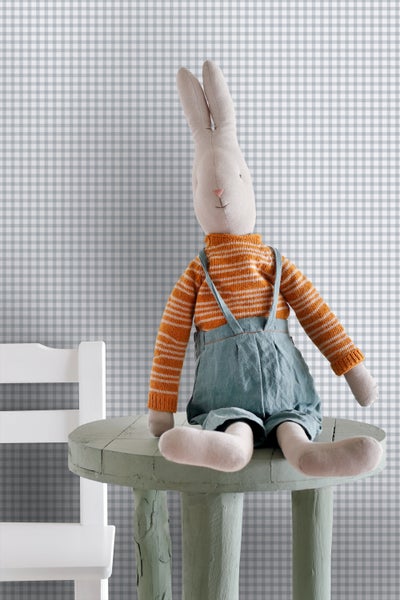 Stoffhase mit gestreiftem Pullover und Latzhose sitzt auf einem kleinen Tisch