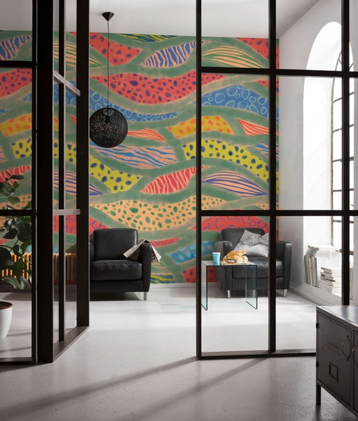 Wohnzimmer mit gemusterter Tapete, Sessel und Glastisch