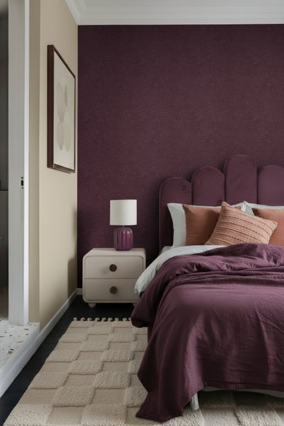 Schlafzimmer mit Bett, Nachttischlampe, Nachttisch und gemusterter Tapete