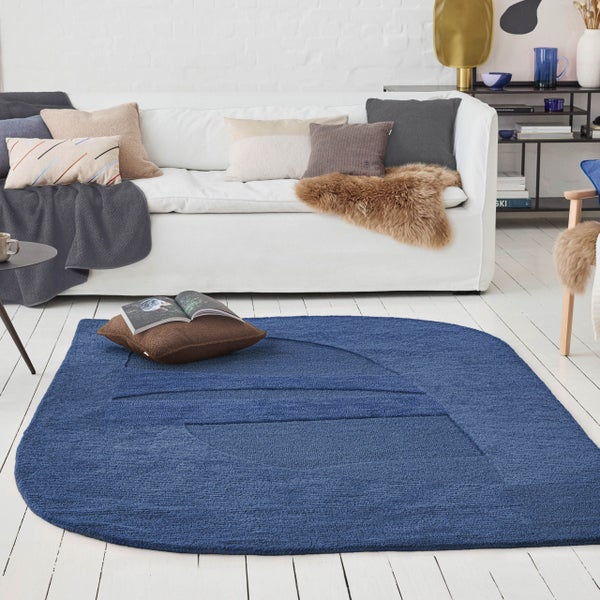 Blauer Teppich mit geometrischem Muster und abgerundeter Form, strukturierte Oberfläche.