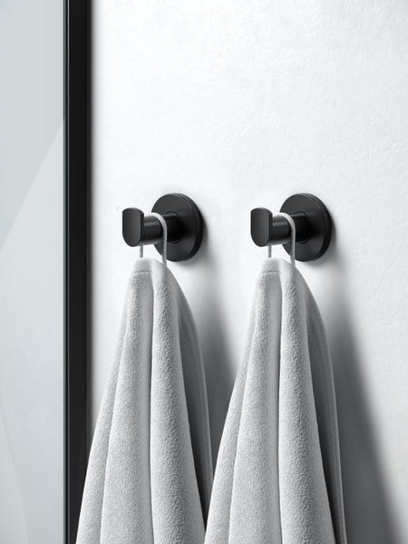 Zwei runde Handtuchhaken an einer Wand mit hängenden Handtüchern im Badezimmer.