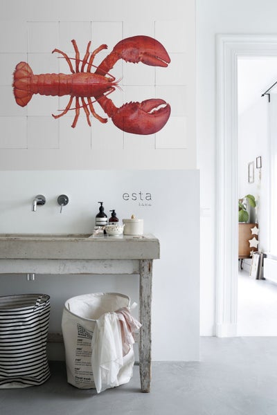 Heller Raum mit Waschbecken, Wäschekörben und einer Fliesenwand mit einem Hummerbild