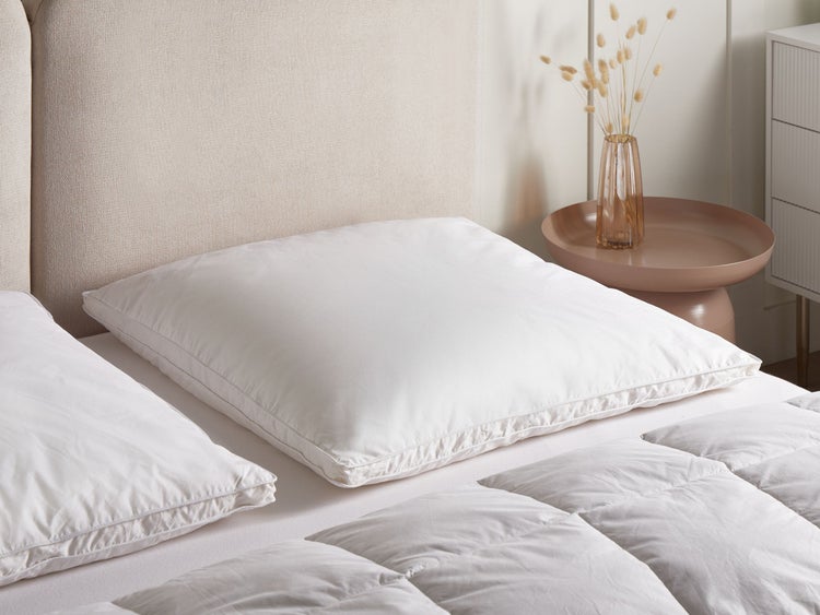 Weißes Kopfkissen auf einem Bett mit Nachttisch und Dekoration