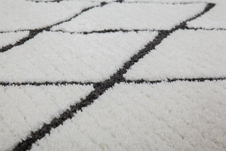 Weißer Hochflor-Teppich mit dunkelgrauem geometrischem Linienmuster, Detailansicht der weichen Textur.