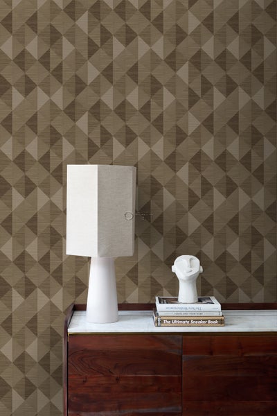 Innenraum mit geometrischer Tapete, Lampe und Dekorationsgegenständen auf einem Holzschrank