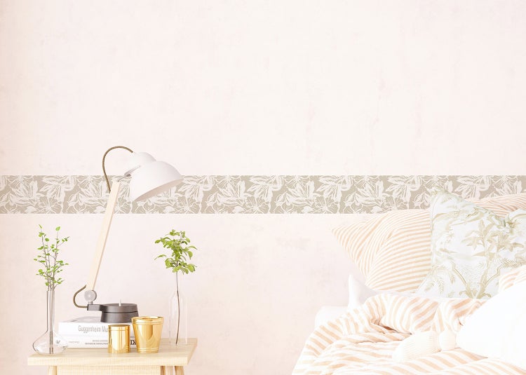 Selbstklebende Wandbordüre mit floralem Muster an einer hellen Wand über einem Sofa mit Kissen und Birnen in einer Schale.