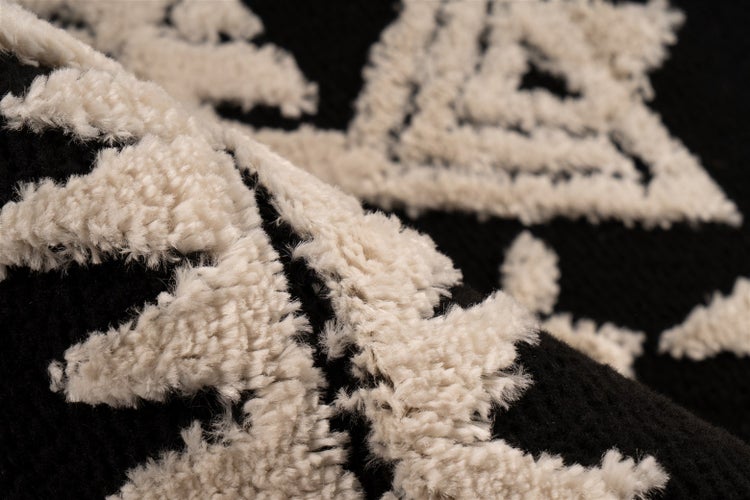 Nahaufnahme eines schwarz-weißen Teppichs mit geometrischem Hoch-Tief-Muster und weicher Textur.