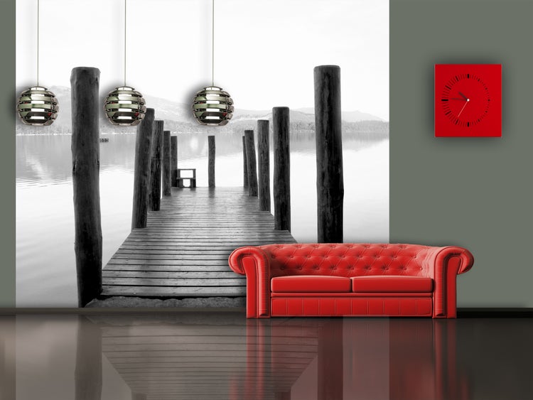 Interieuransicht mit rotem Sofa, Wanduhr und Fototapete mit Seebrückenmotiv