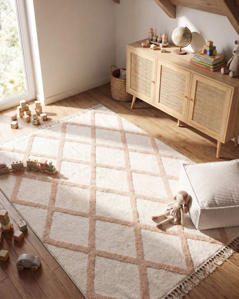 Heller Kinderzimmerteppich mit Rautenmuster, Fransen und texturierter Oberfläche in einem gemütlichen, mit Holzmöbeln eingerichteten Zimmer.