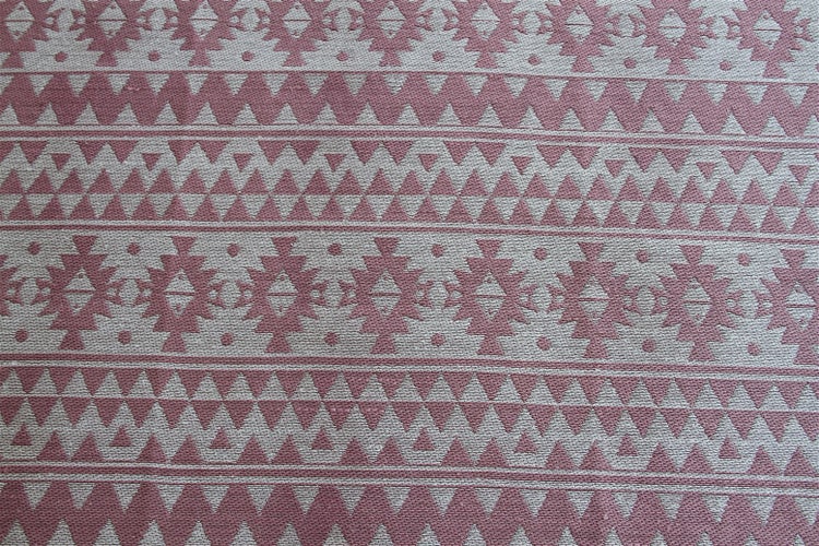 Textiloberfläche mit geometrischem Ethno-Muster aus Reihen von Dreiecken und Zickzack-Linien.