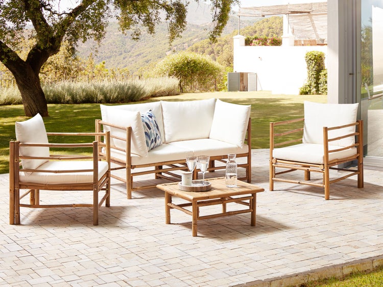 Gartenmöbelset aus Bambus mit Sofa, Sessel und Tisch auf einer Terrasse.