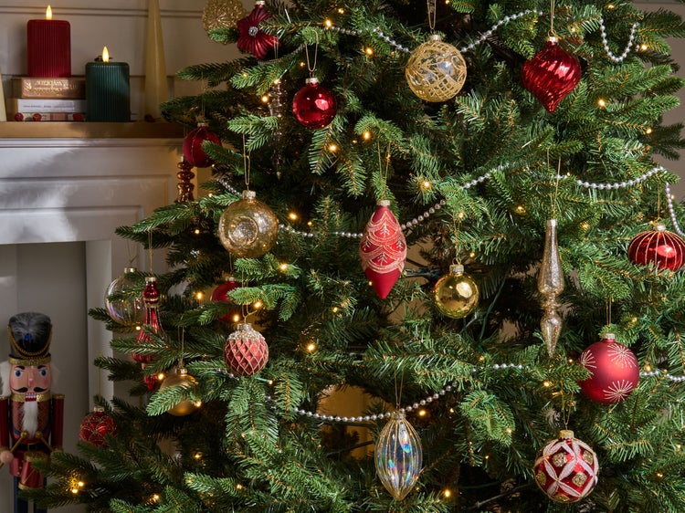 Dekorierter Weihnachtsbaum mit Christbaumkugeln, Lichterkette, Weihnachtsmann und Kerzen