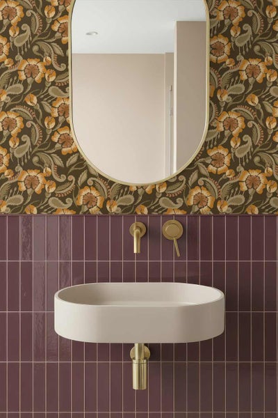 Modernes Badezimmer mit floraler Tapete, ovalem Spiegel, hellbeigem Wandwaschbecken, vertikalen lila Fliesen und goldenen Armaturen.