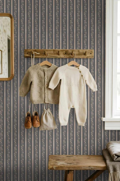 Vliestapete mit floralem Streifenmuster in einem hellen, rustikalen Zimmer mit Holzmöbeln und Kinderkleidung an einer Garderobe.