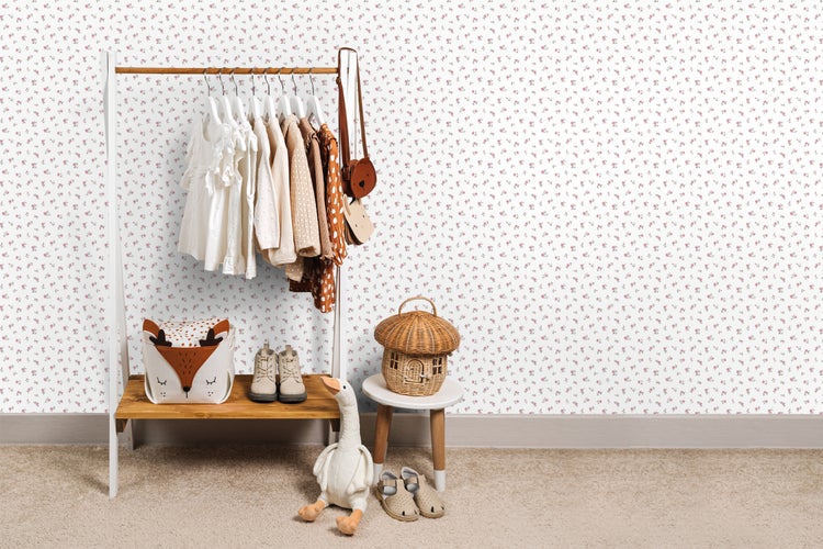 Kinderzimmer mit Kleiderständer, Kleidung, Spielzeug und Blumentapete