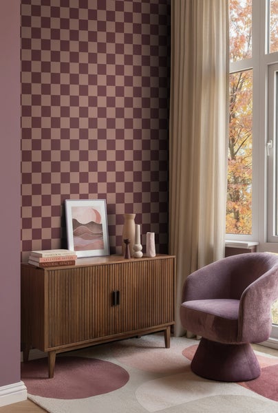 Vliestapete mit Karomuster in einem modern eingerichteten Wohnzimmer mit Holzkommode und Sessel.