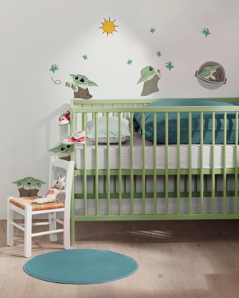 Kinderzimmer mit Gitterbett, Kinderstuhl und Wanddekoration.