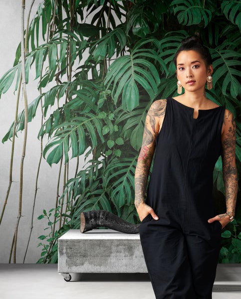 Raumgestaltung mit Pflanzenmotivtapete, Betonsitzbank und dekorativem Holzstück