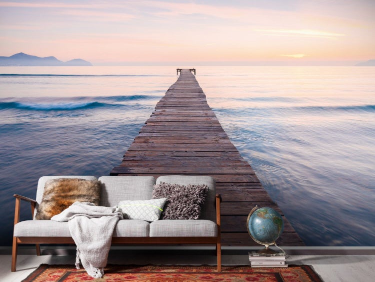 Wohnzimmer mit Fototapete eines Piers, der ins Meer führt und eine ruhige, helle Atmosphäre schafft