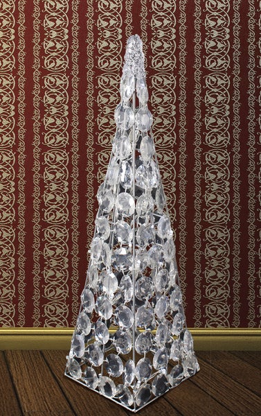 Dekorativer Kristallbaum auf Holzboden vor gemusterter Tapete