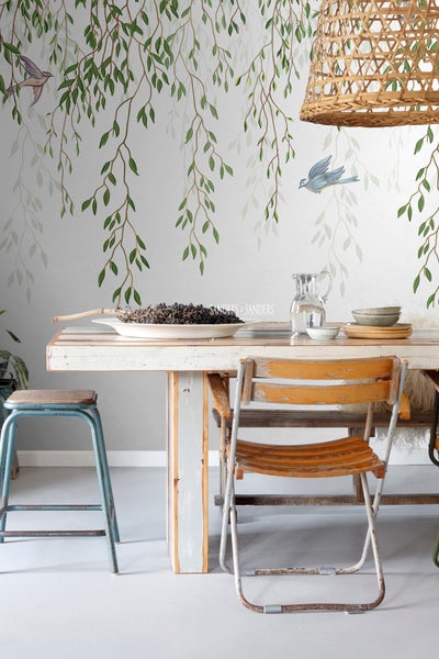 Esszimmer mit Holztisch, Stühlen und Wanddekoration mit Blättern und Vögeln