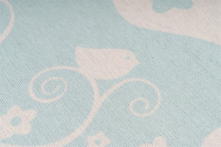 Nahaufnahme eines gewebten Teppichs mit Vogel- und Blumenmuster sowie gerippter Oberflächenstruktur.