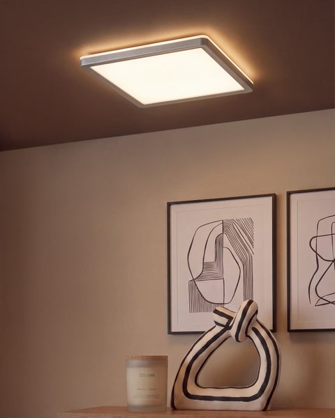 Quadratische LED Deckenleuchte in einem modern eingerichteten Wohnraum mit abstrakter Wandkunst und dekorativen Wohnaccessoires.