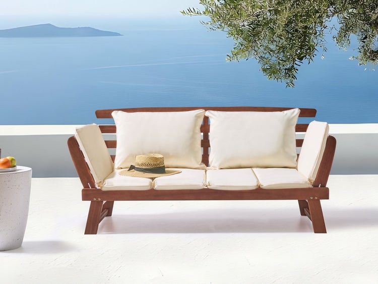 Holzbank mit Kissen und Hut im Außenbereich mit Meerblick