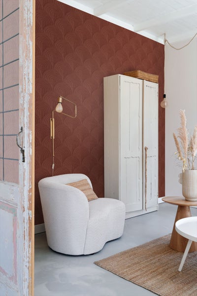 Wohnzimmer mit gemusterter Tapete, Sessel und Holzmöbeln für eine gemütliche Atmosphäre.