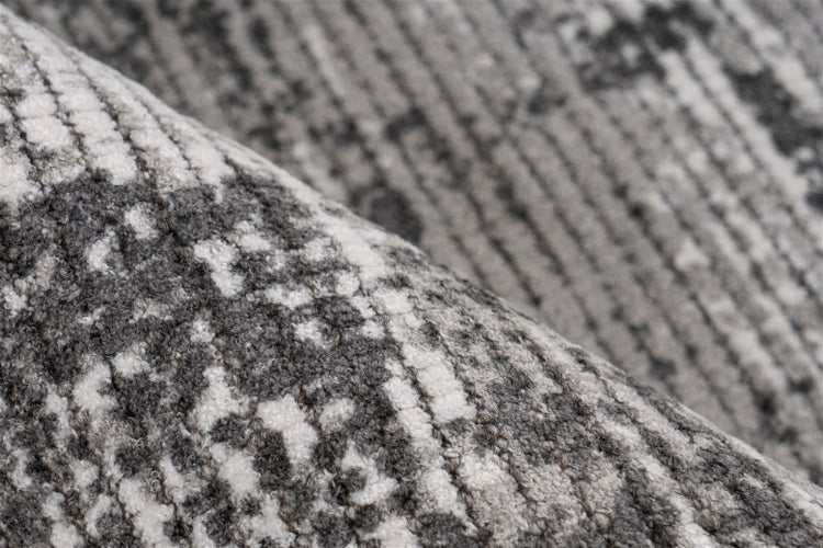 Nahaufnahme eines gewebten Teppichs mit grau-weißem abstraktem Streifenmuster.