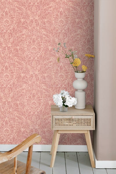 Rosa gemusterte Tapete an einer Wand mit Beistelltisch und Blumen