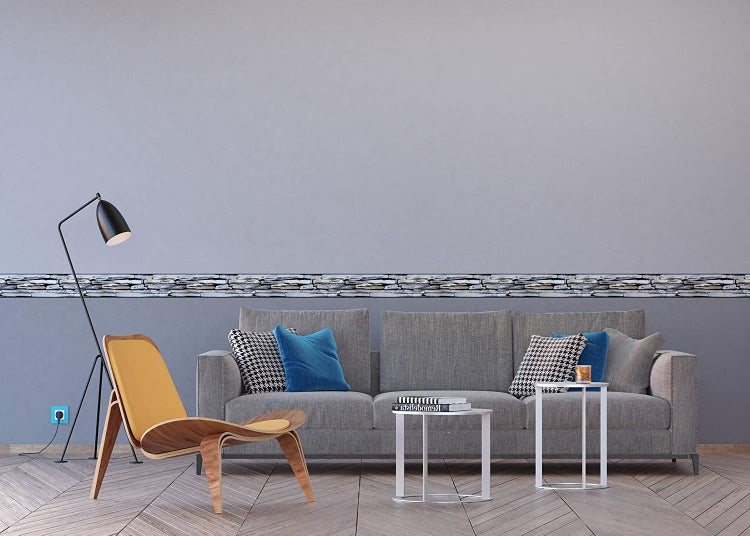 Wohnzimmer mit Sofa, Sessel, Stehlampe, Beistelltischen und Bordüre in Steinoptik