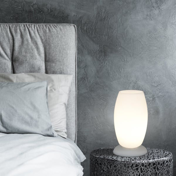 Nachttischszene mit Bett, dekorativer Lampe und Beistelltisch