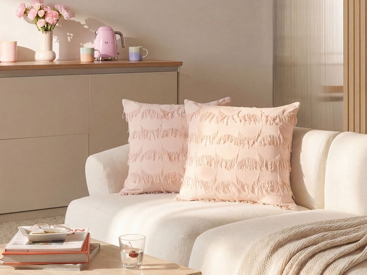 Helles Wohnzimmer mit zwei strukturierten Zierkissen mit kreisförmigem Fransenmuster auf einem modernen Sofa.