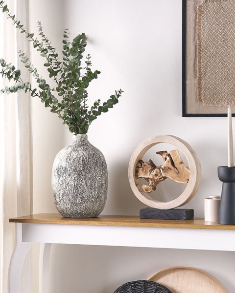 Dekorative Szene mit Eukalyptus in Vase, Holzskulptur und Kerzenständer auf einem Tisch