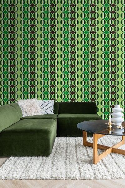 Wohnzimmer mit grüner Couch, Teppich und geometrischer Tapete