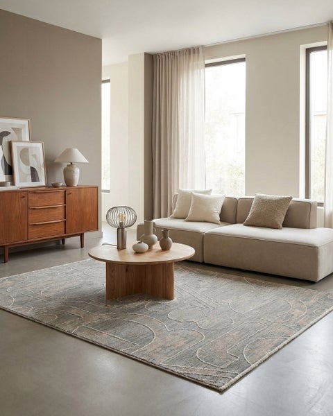 Modernes, helles Wohnzimmer mit einem gemusterten Teppich, einem beigefarbenen Sofa, einem runden Couchtisch aus Holz und einem hölzernen Sideboard.
