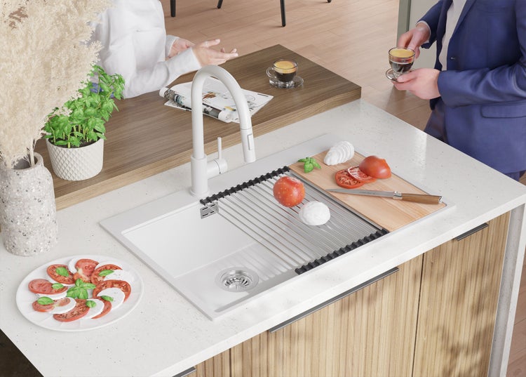Küchenspüle mit Abtropfgestell, Armatur, Tomaten und Mozzarella auf einem Schneidebrett
