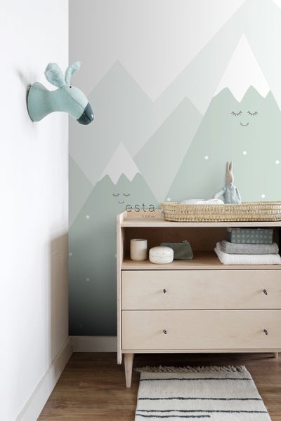 Babyzimmer mit Kommode, Wanddekoration mit Bergmotiven und Stofftierkopf an der Wand.