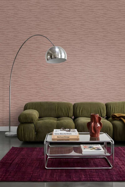 Wohnzimmer mit Vliestapete mit Wellenmuster, grünem Sofa, Couchtisch aus Glas und Metall sowie Bogenleuchte.
