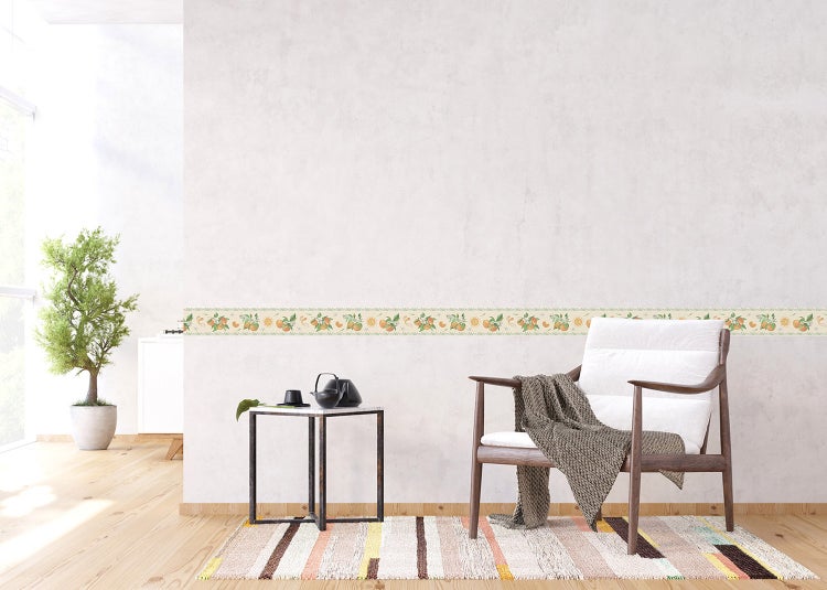 Hell eingerichtetes Wohnzimmer mit einer selbstklebenden Tapetenbordüre mit Orangenmotiv an der Wand, einem Sessel und einem Beistelltisch.