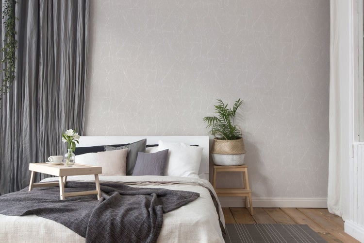 Helles Schlafzimmer mit gemusterter Tapete, Bett und Dekorationen